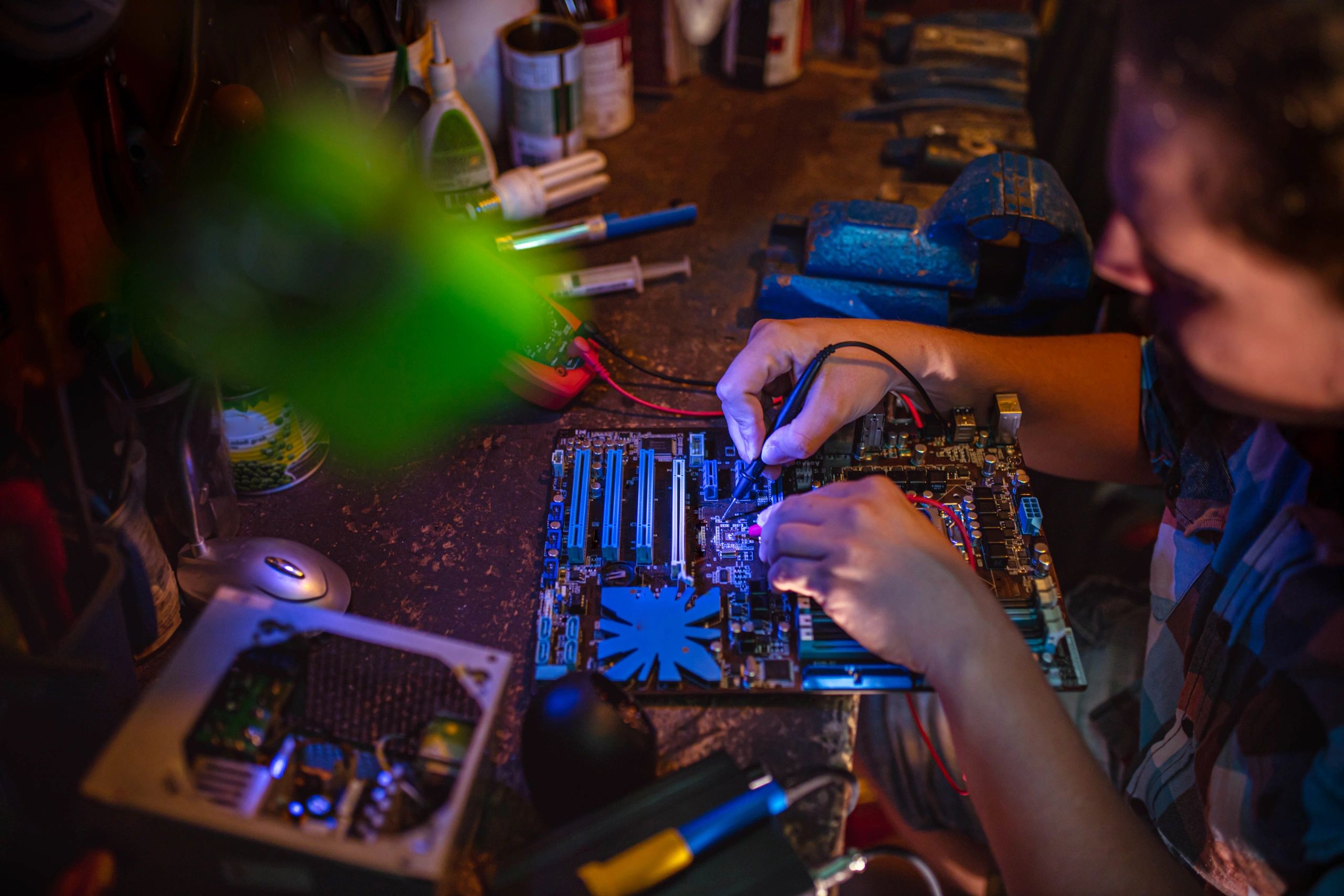 Technician testing a computer motherboard with a multimeter