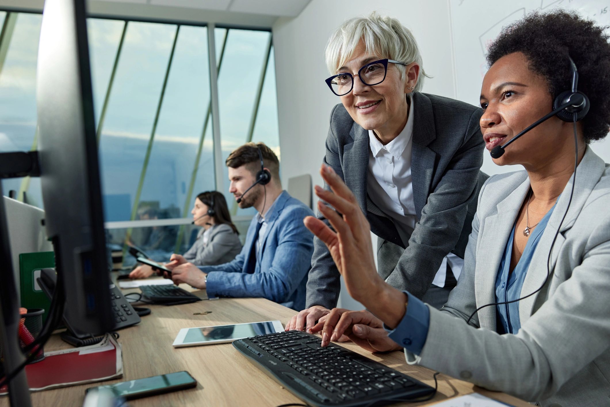 IT support manager assisting an employee at a workstation