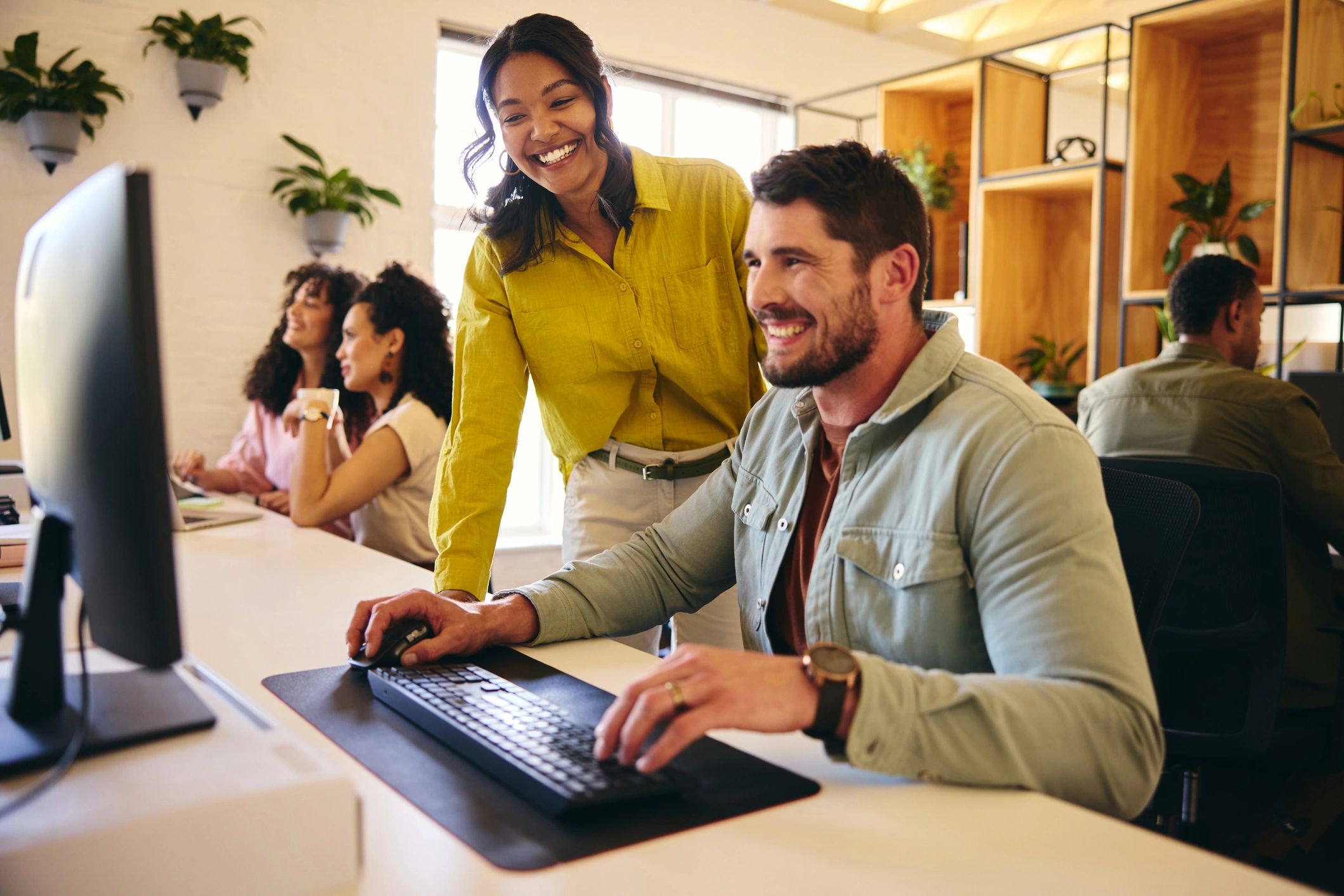 Two colleagues reviewing a computer screen and discussing IT support